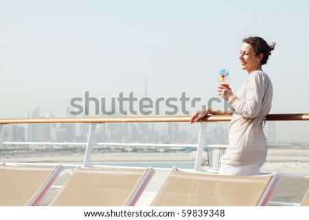 young beauty woman with cocktail standing on cruise liner deck, half body