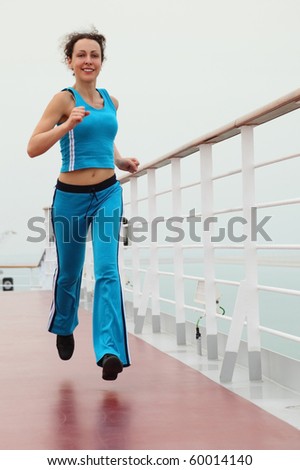 young beauty girl in sport dress running on cruise liner deck, looking at camera