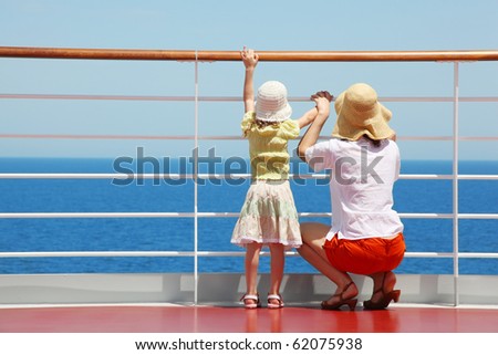behind mother and her daughter standing on deck of yacht and they look far aboard