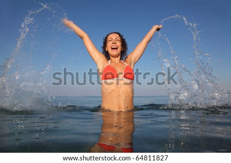 Young beautiful woman wearing red bathing suit jumping in sea. drops from her hair fly. from the underwater package