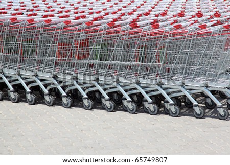 Set of stacked supermarket trolleys with red handle out of doors