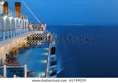 Illuminated cruise ship with people in the sea at night near city