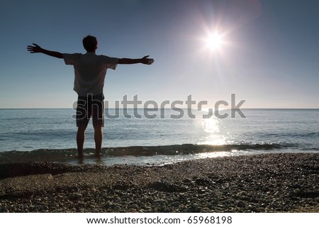 Man stands ashore in water and conducts hands in sides
