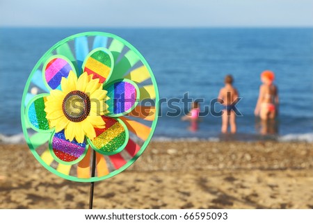 multicolored pinwheel toy with flower on beach, family standing in water