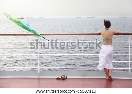 beautiful woman standing on deck of cruise ship and looking away.
