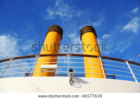 two yellow pipes on big cruise ship. camera and wires. lamps.