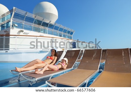 woman and her daughter both wearing swimsuit on chaise lounge