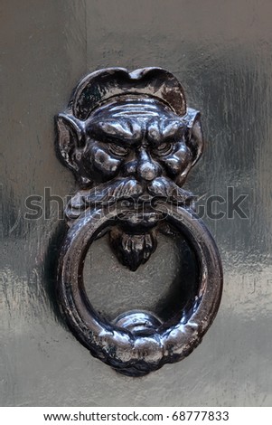 big beautiful metal doorknob, holding human head in his mouth stick
