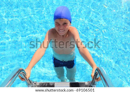Boy in dark blue little cap and melting entering in water in  pool