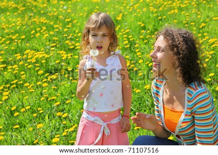 Mother plays with  girl which breath on  dandelion and  from it parachute fly