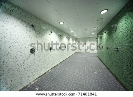 big, light, empty public shower room, green tile on walls, gray floor