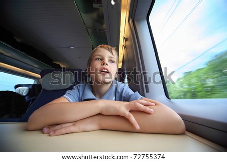 Boy rides in  speed train and looks through window