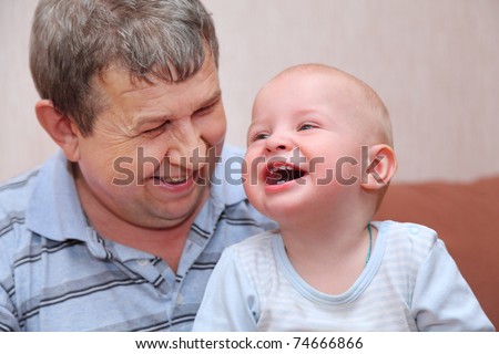 Portrait of laughing, happy old man and his grandson, focus on little baby tooth