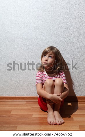 Little girl in casual clothes looks sad to corner, whence comes the light