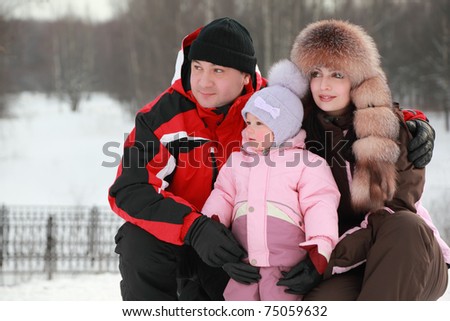father hugs mother and little daughter at snow, they looks into distance, winter, focus on girl
