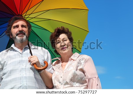 portrait of old woman and man holding multicolored umbrella