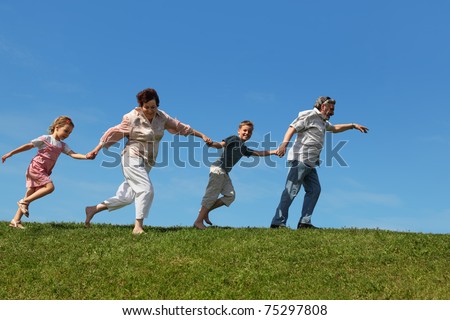 grandchildren and their grandparents running on lawn and holding for hands, side view
