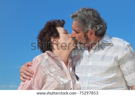 portrait of old man and woman kissing lips, blue sky