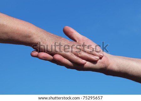 closeup of old man holding hand of old woman, blue sky