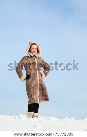 Girl putting hands on waist  stands on snow in winter