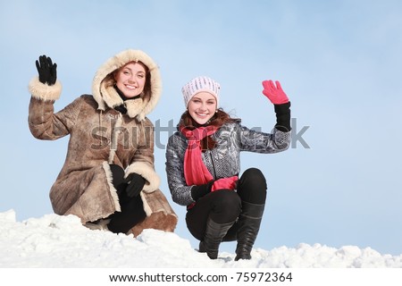 stock photo Two girls squatting on snow and waff onearm