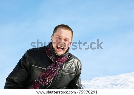 Young man laughs merrily in day-time in street in winter