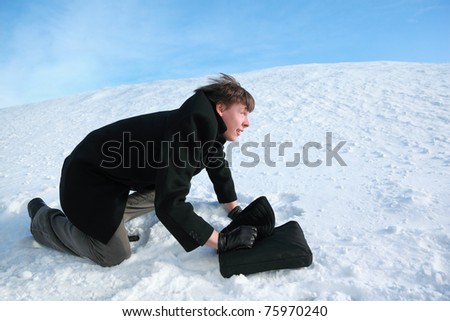 Young man creeps on all fours on snow with  brief-case