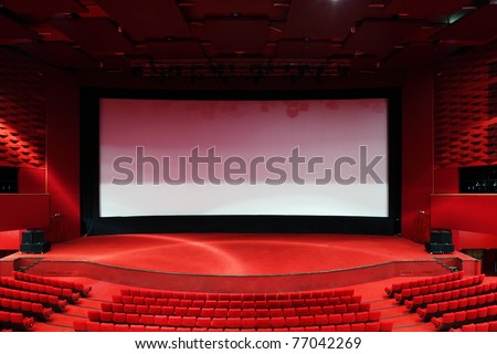High-angle view of screen and rows of comfortable red chairs in illuminate red room cinema