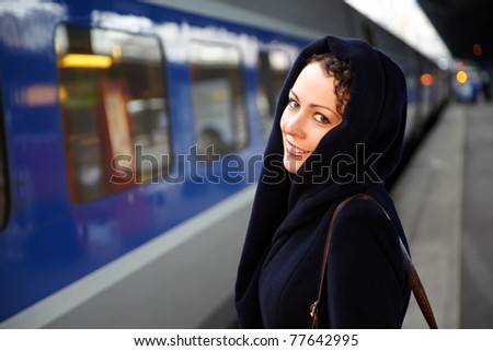 Young smiling woman close-up stands on the platform near the train.