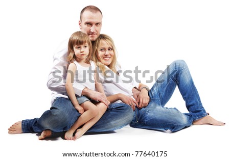 Father, mother and little daughter in white shirts and jeans sit on the floor.