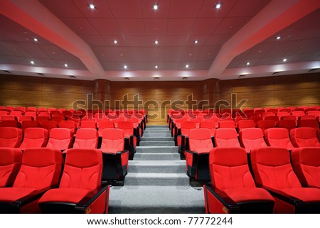 Rows of red arm-chairs are in  empty hall