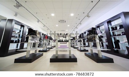 Black shelves with many boots and shoes into large shoe store