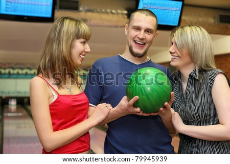 Two girls and man stand alongside and laugh merrily, focus on man