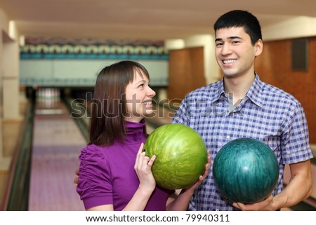 Young man and girl hold balls for bowling and laugh merrily