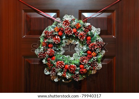 Large artificial circled wreath with knops and bead hangs during Christmas on door
