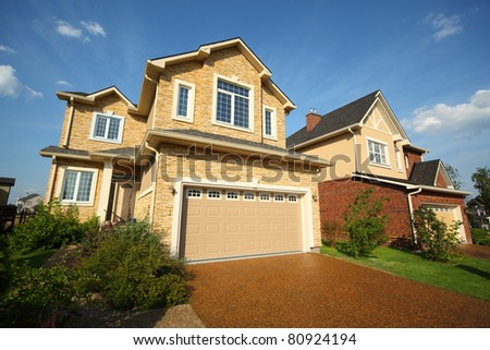 Two new two-storied beige stone and brick cottage with garage and garden.