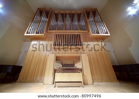 Massive wooden pipe organ with long metal tubes; control panel