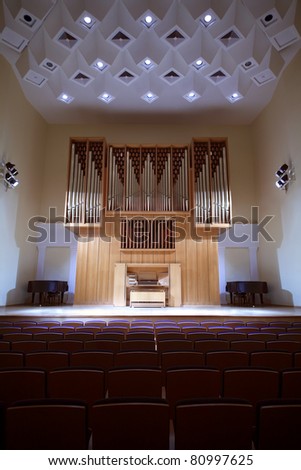 Massive wooden pipe organ with control panel in empty concert hall