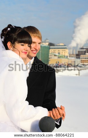 happy groom and bride holding hands at winter outdoors, couple standing on bridge