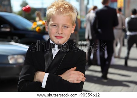 little boy dressed in tuxedo and bow tie standing at sunny day outdoor