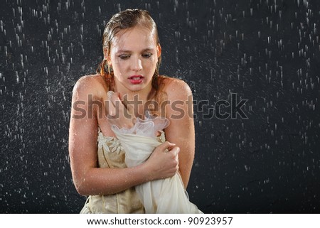 beautiful girl wearing in dress with corset freezes in rain and tries to keep warm