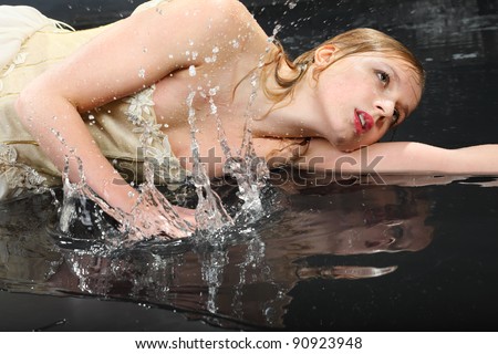 beautiful thoughtful girl wearing in dress with corset lies on wet floor and sprays water