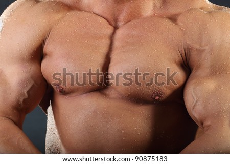 Strong chest and hand muscles of undressed tanned wet bodybuilder