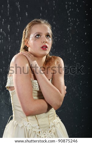 beautiful girl wearing in dress with corset freezes in rain, tries to keep warm and looks up