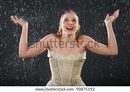 happy beautiful girl wearing in dress smiles in rain and catches drops by hands