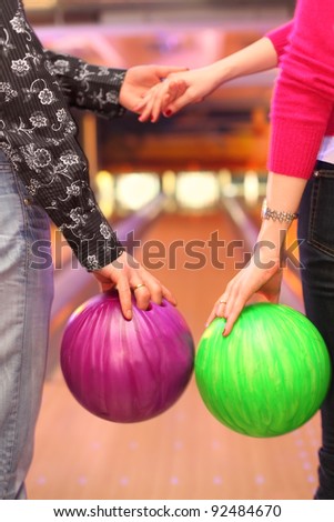 Female and male hands with balls in bowling club; man and woman holding hands