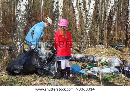 Back of brother and sister with black bags collect last year trash in park at spring