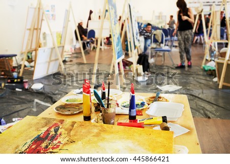 Table with paints in tubes, brushes and paint-roller in art room.