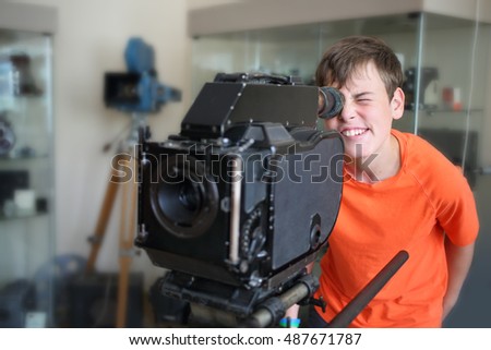 The young man in orange t-shirt looking at the old camera in a museum