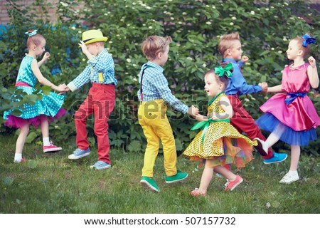 Three children couples dance on grassy lawn outdoor.